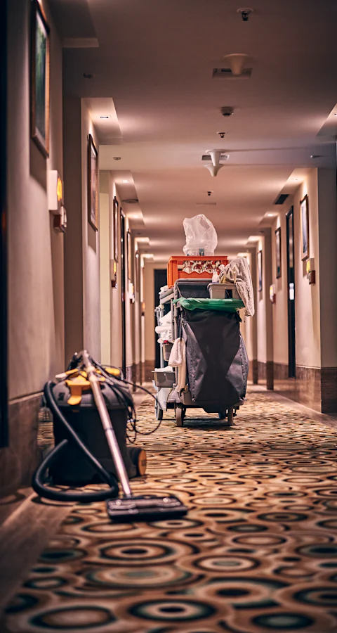 Reinigungswagen mit Staubsauger auf einem gemusterten Hotelflur